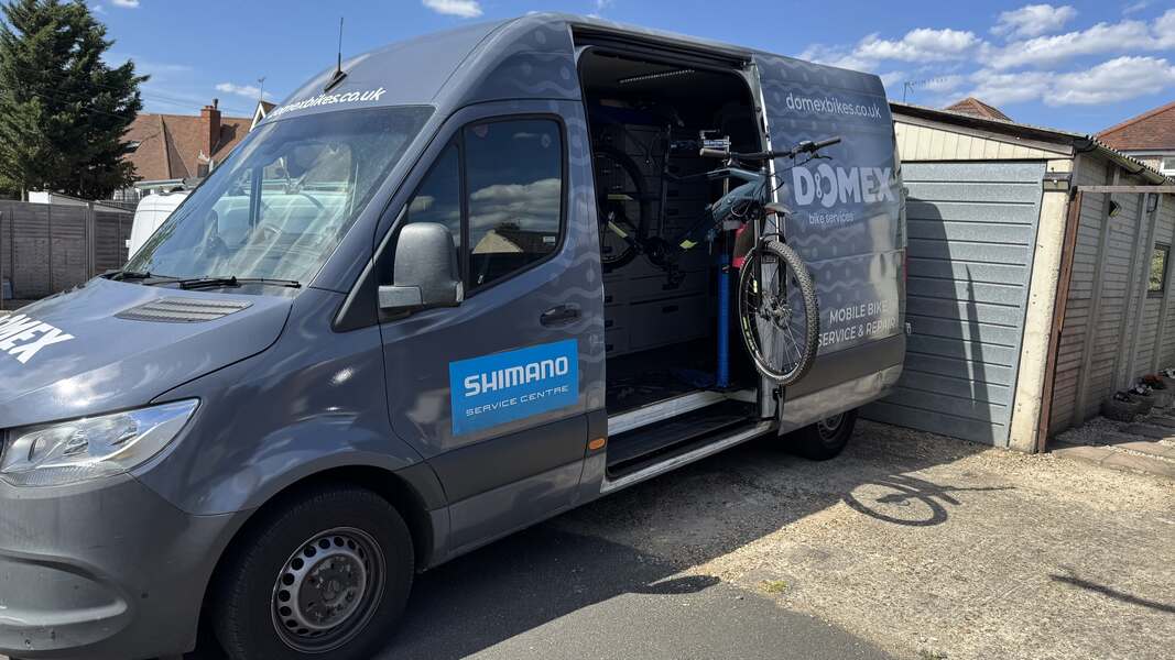 A van with a bicycle in the back, promoting Domex Bikes' mobile e-bike repair services