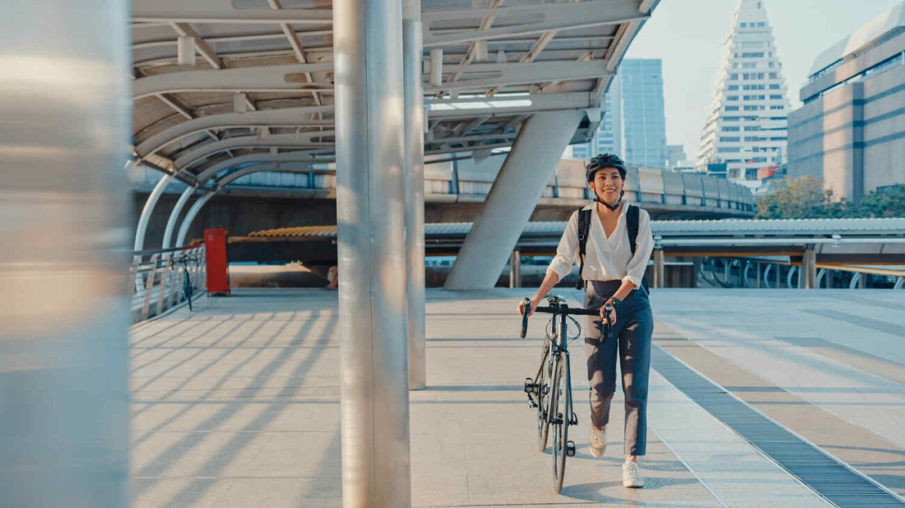 Professional commuter walking her bike through a city business district on the way to the office