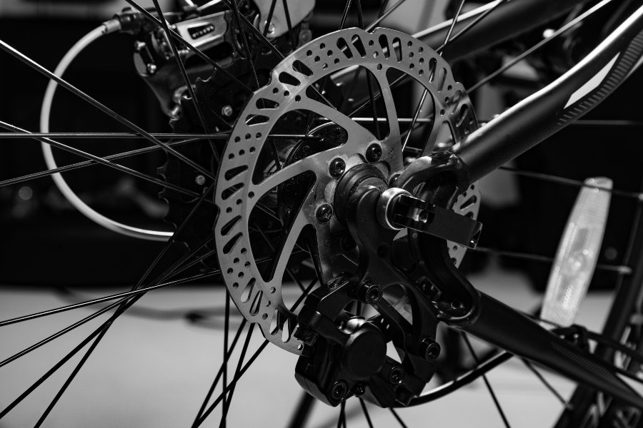 Close-up view of a bicycle hydraulic disc brake caliper and rotor assembly mounted on the rear wheel.