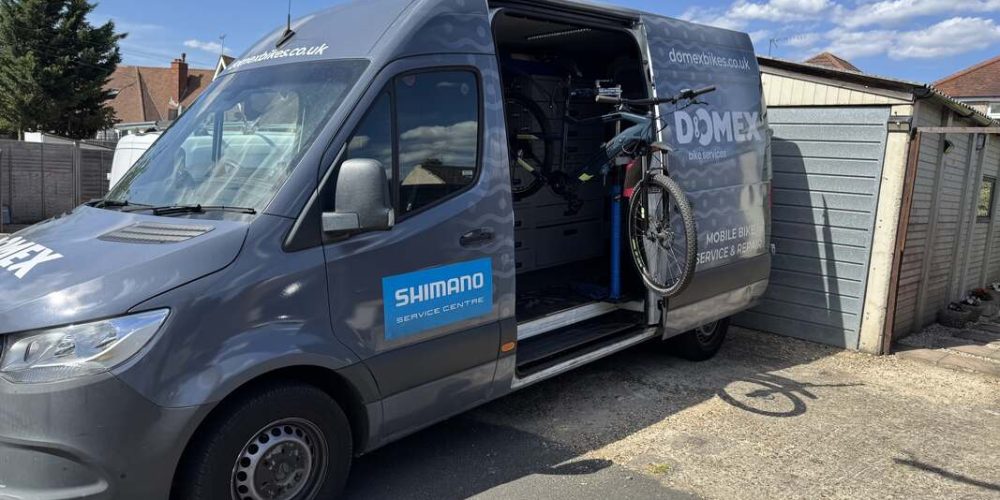 A van with a bicycle in the back, promoting Domex Bikes' mobile e-bike repair services